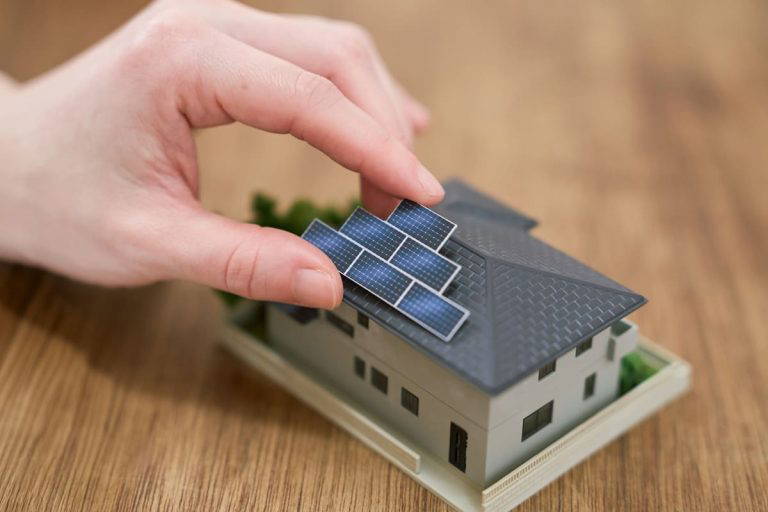 Hand placing solar panels on a small toy house
